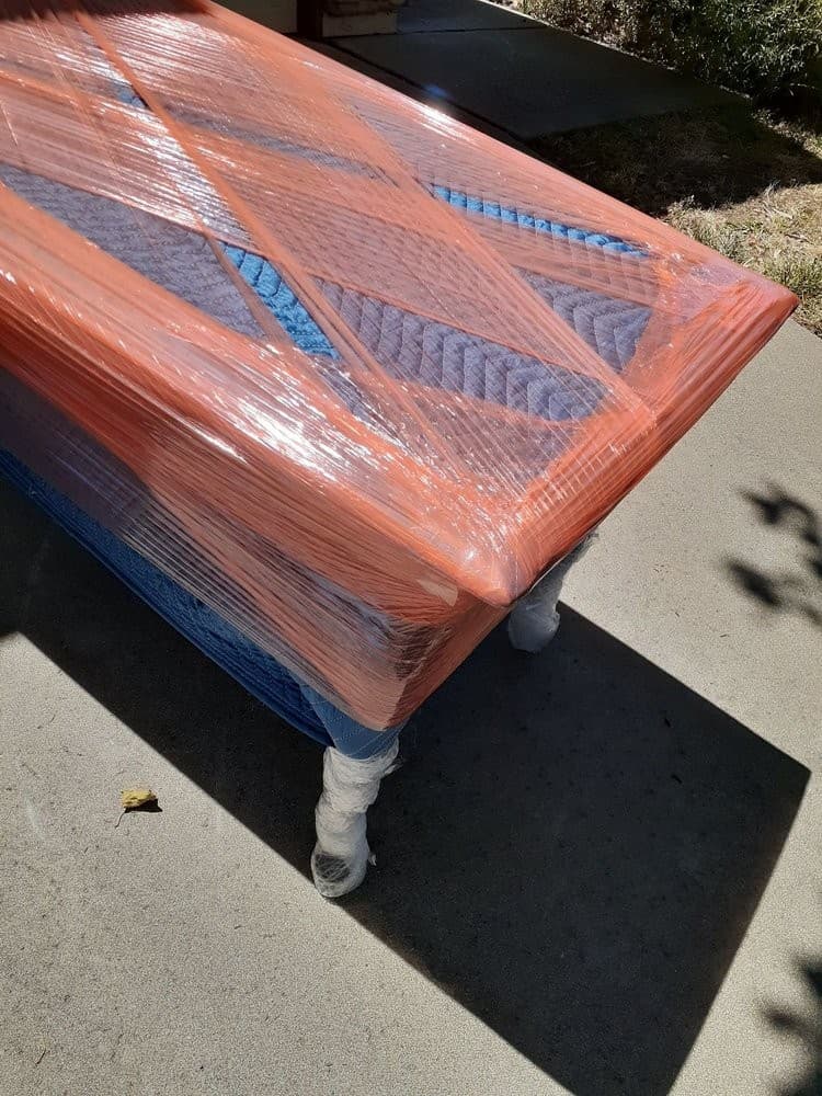 Large dining table securely wrapped with blankets and stretch wrap for moving in Sacramento.